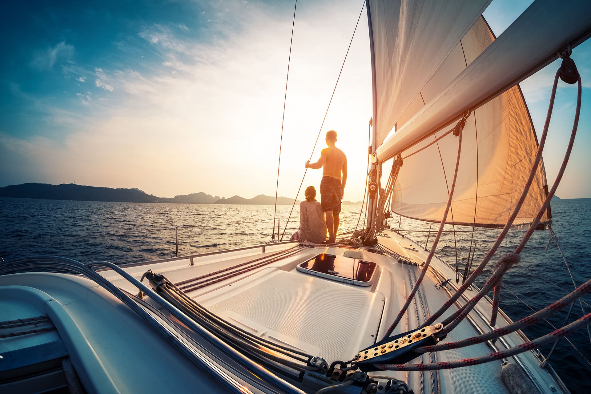 Symbolfoto für Steuerberatung Thüringen: Paar genießt Sonnenuntergang vom Deck eines Segelbootes im Meer